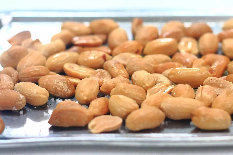 A close-up photo of roasted peanuts on a tray